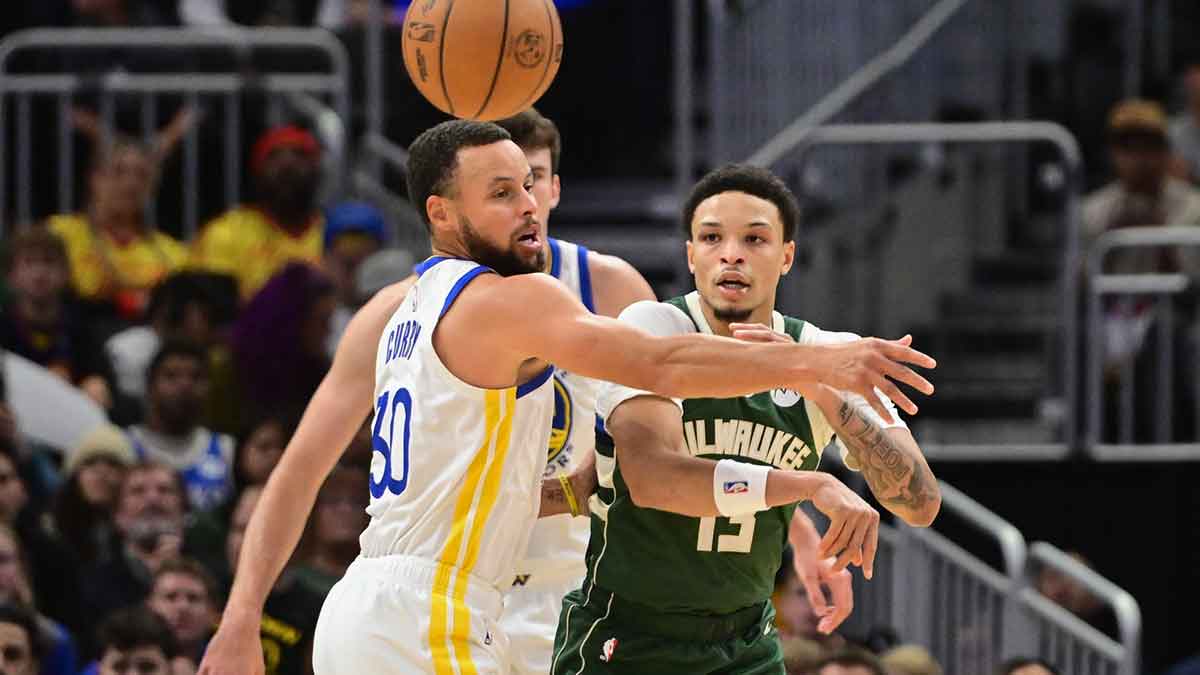 Milwaukee Bucks guard Ryan Rollins (13) passes the ball away from Golden State Warriors guard Stephen Curry (30) in the first quarter at Fiserv Forum.