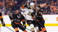 Anaheim Ducks center Trevor Zegras (11) is checked off the puck by Philadelphia Flyers left wing Noah Cates (49) and left wing Joel Farabee (86) during the second period.
