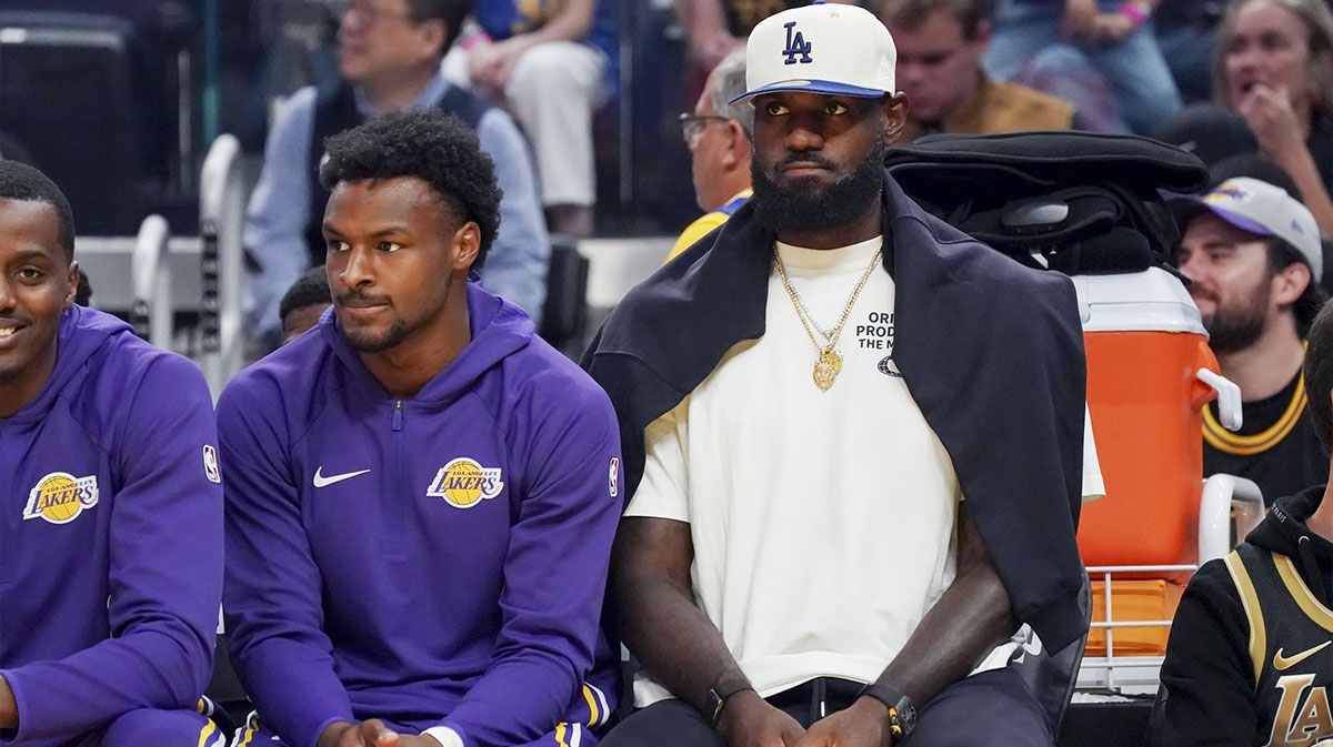 Los Angeles Lakers guard Bronny James (9) and forward LeBron James (23), wearing a Los Angeles Dodgers cap, watch the action against the Golden State Warriors in the first quarter at Chase Center.