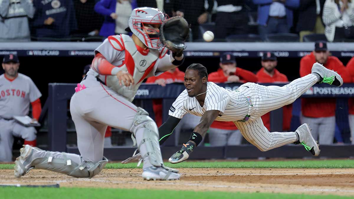 New York Yankees second baseman Jazz Chisholm Jr. (13) scores the game winning run against Boston Red Sox catcher Carlos Narvaez (75) on a single by New York Yankees catcher Austin Wells (not pictured) during the eighth inning of game two of the Wildcard round of the 2025 MLB playoffs at Yankee Stadium.
