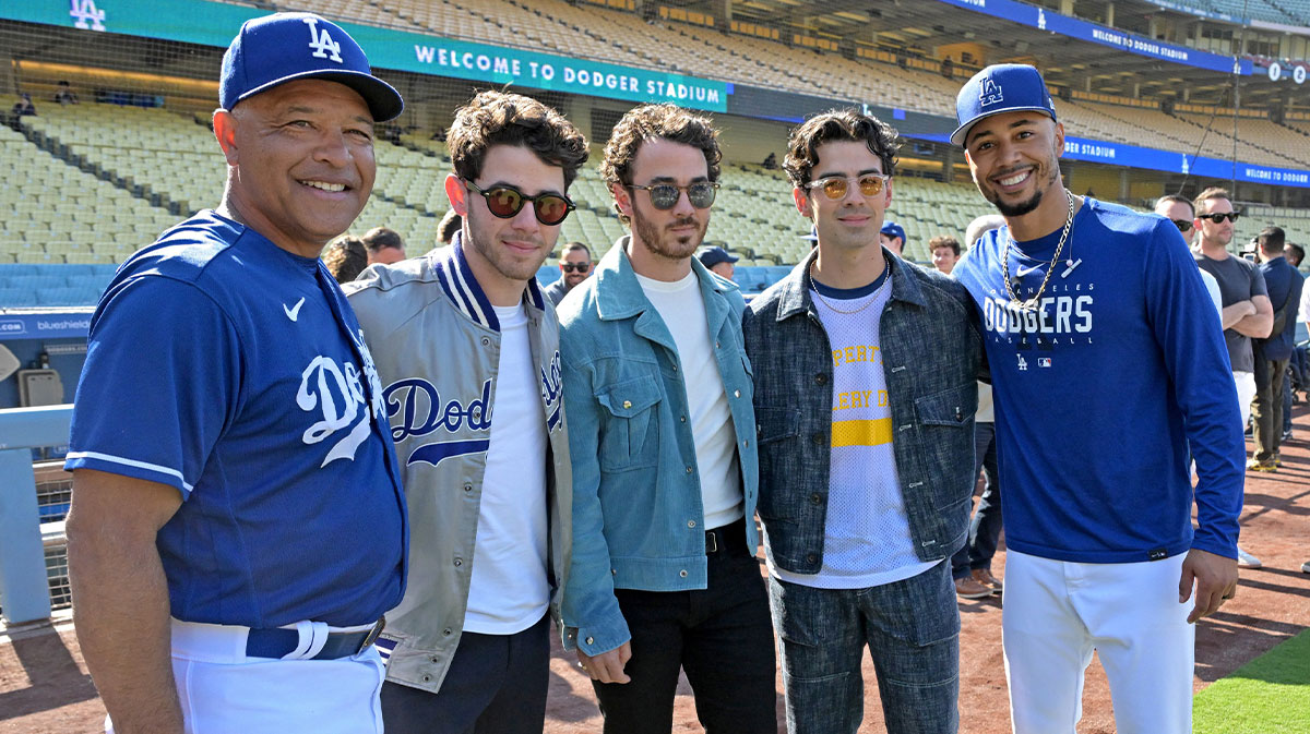 Los Angeles Dodgers manager Dave Roberts (30) and right fielder Mookie Betts (50) meet with the Jonas Brothers Nick, Kevin, and Joe on the field prior to the game against the Houston Astros at Dodger Stadium.