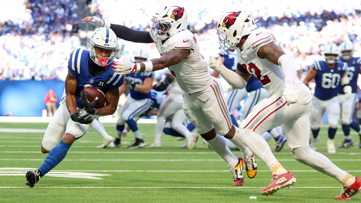 Indianapolis Colts wide receiver Josh Downs (1) carries the ball defended by Arizona Cardinals linebacker Mack Wilson (2) and safety Dadrion Taylor-Demerson (42) during the fourth quarter of the game at Lucas Oil Stadium.