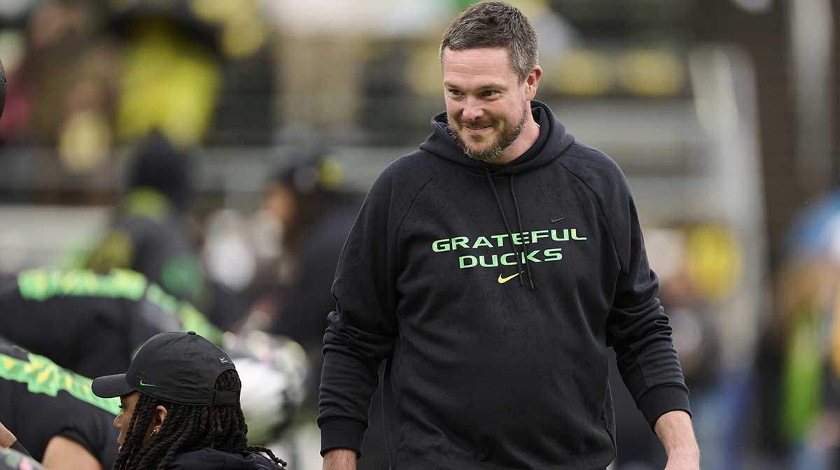 Oregon Ducks head coach Dan Lanning encourages players during warm ups before a game against the Wisconsin Badgers at Autzen Stadium. The Ducks are wearing uniforms celebrating the Grateful Dead.