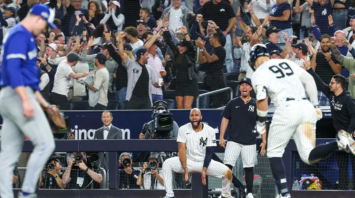 New York Yankees outfielder Aaron Judge (99) hits a three-run home run as players in the dugout celebrate in the fourth inning against the Toronto Blue Jays during game three of the ALDS round for the 2025 MLB playoffs at Yankee Stadium.