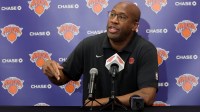Knicks head coach Mike Brown speaks to the media during a media day press conference at the Madison Square Garden training center with Knicks' Pacome Dadiet and Knicks open roster in the background