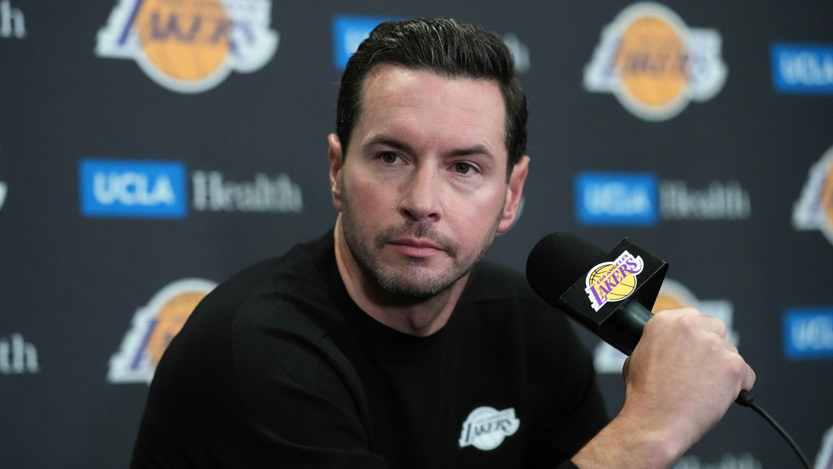 Lakers head coach JJ Redick at a press conference at Crypto.com Arena with Lakers fan base in the background
