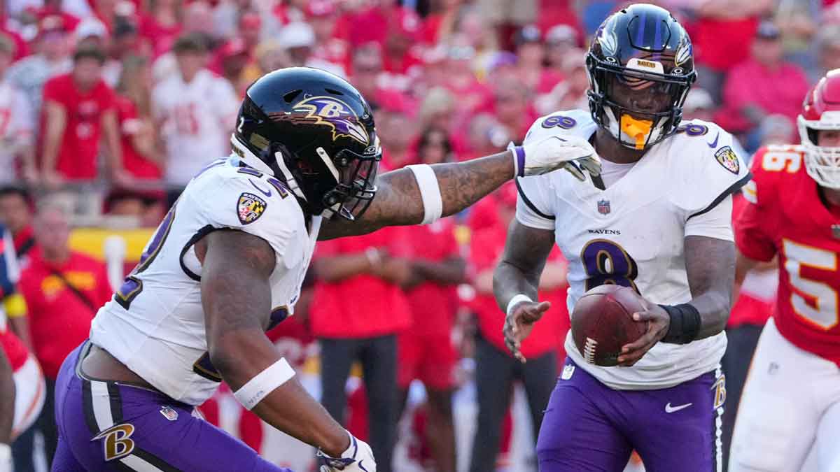 Baltimore Ravens quarterback Lamar Jackson (8) hands off to running back Derrick Henry (22) against the Kansas City Chiefs during the game at GEHA Field at Arrowhead Stadium.