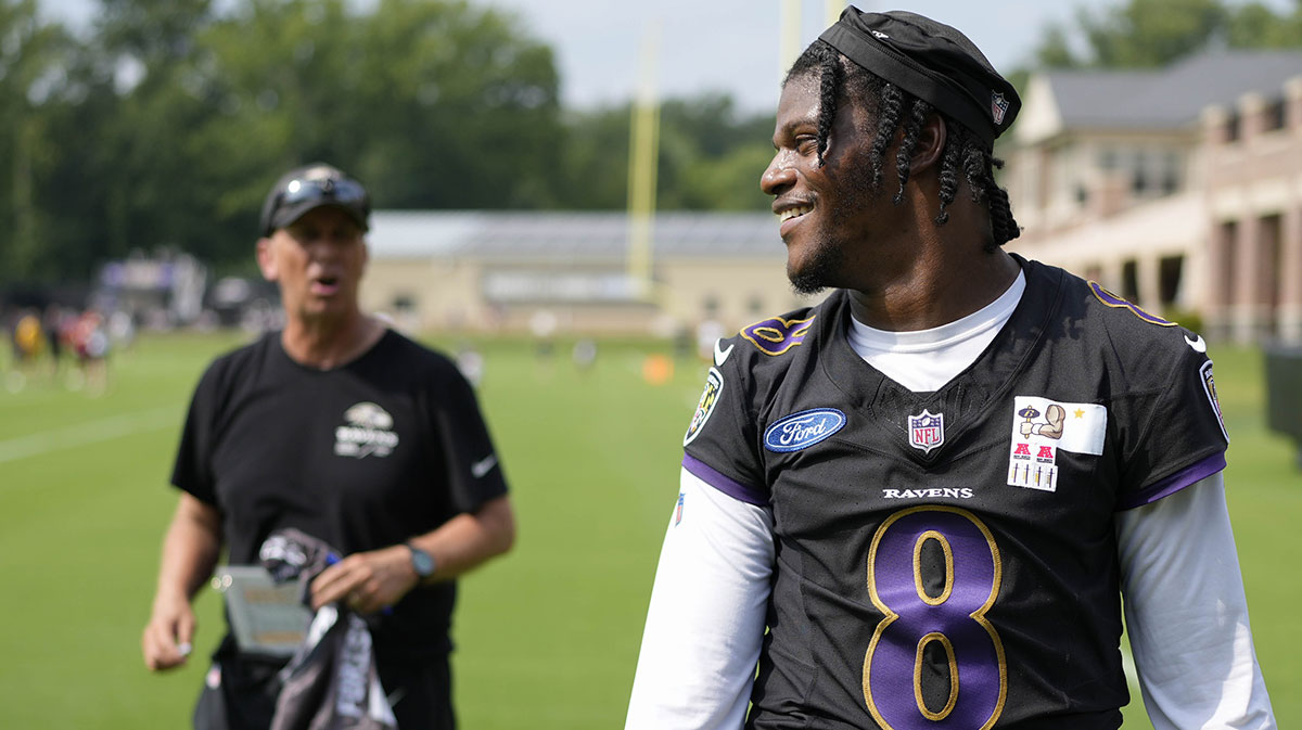 Baltimore Ravens quarterback Lamar Jackson (8) smiles at a fan with Baltimore Ravens offensive coordinator Todd Monken standing in the background following training camp practice at Under Armour Performance Center.