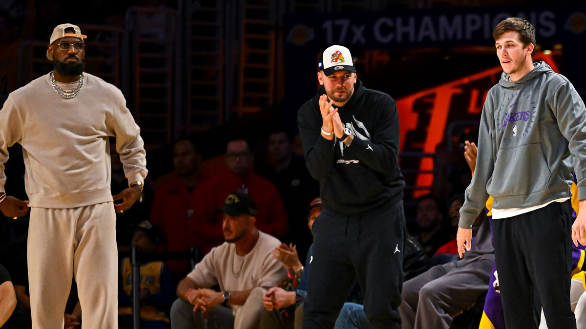 Los Angeles Lakers forward LeBron James (23), guard Luka Doncic (77), and guard Austin Reaves (15) on the sidelines against the Milwaukee Bucks during the first half at Crypto.com Arena.