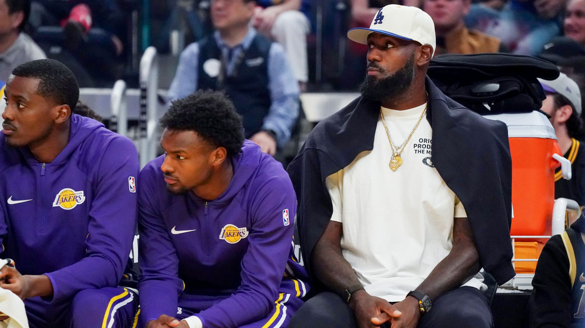 Los Angeles Lakers guard Bronny James (9) and forward LeBron James (23), wearing a Los Angeles Dodgers cap, watch the action against the Golden State Warriors in the first quarter at Chase Center.