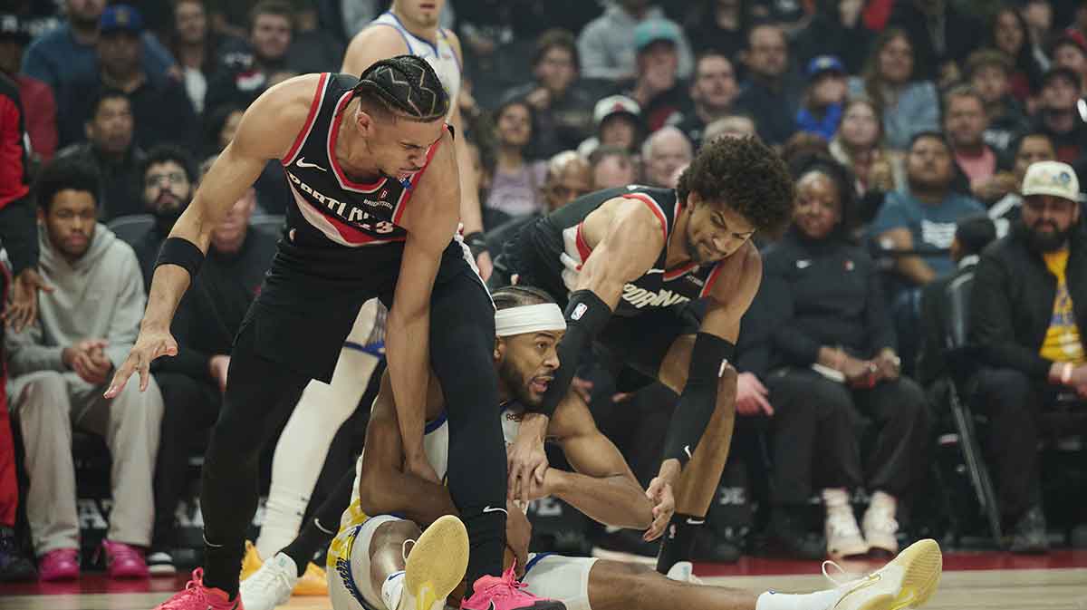 Golden State Warriors guard Moses Moody (4) gets tied up during the first half against Portland Trail Blazers forward Toumani Camara (33), left, and guard Matisse Thybulle (4) at Moda Center.