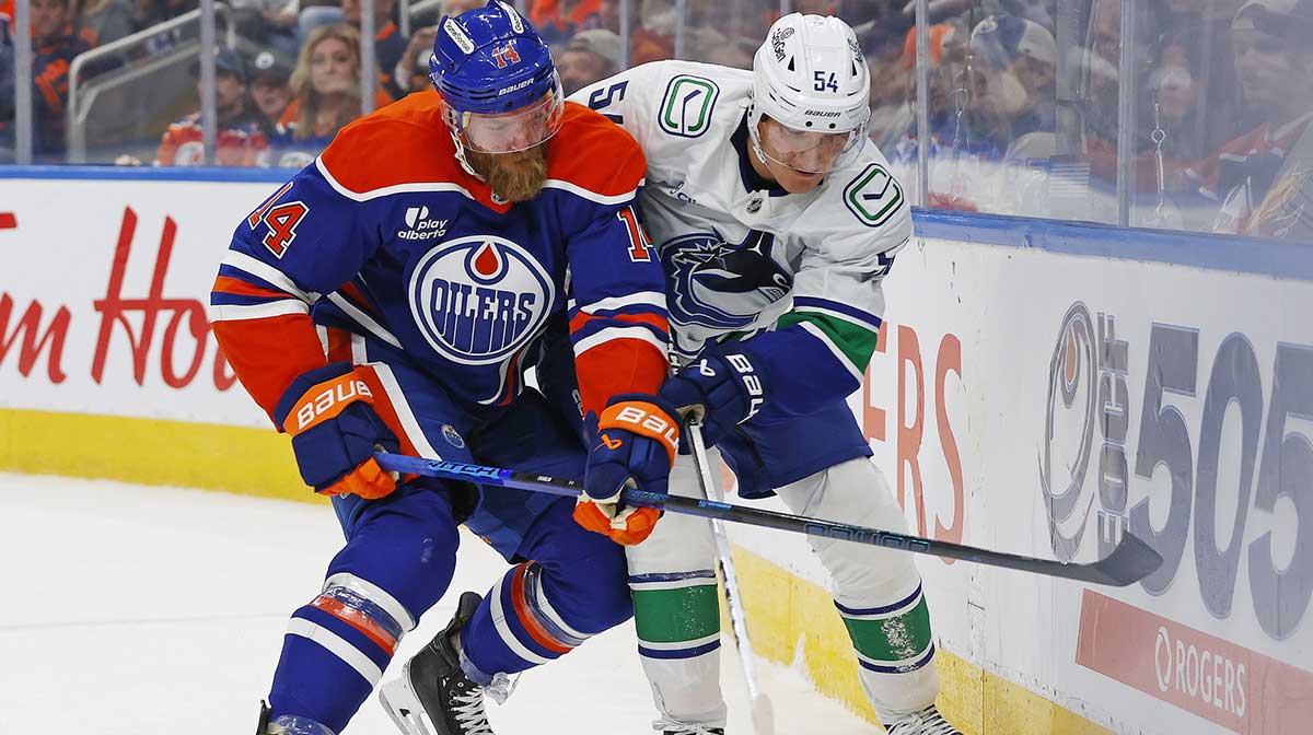 Edmonton Oilers defensemen Mattias Ekholm (14) and Vancouver Canucks forward Aatu Raty (54) battle along the boards for a loose puck during the second period at Rogers Place.