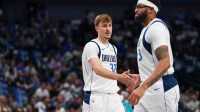 Mavericks forward Cooper Flagg (32) low fives forward/center Anthony Davis (3) in the first half of game against the Charlotte Hornets at American Airlines Center with ESPN's Stephen A Smith in the background & Mavericks championship favorites
