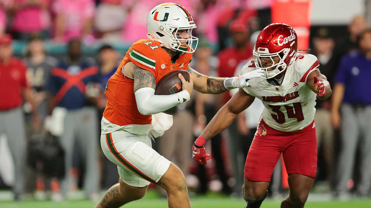Miami Hurricanes quarterback Carson Beck (11) carries the football against Louisville Cardinals linebacker T.J. Quinn (34) during the third quarter at Hard Rock Stadium.
