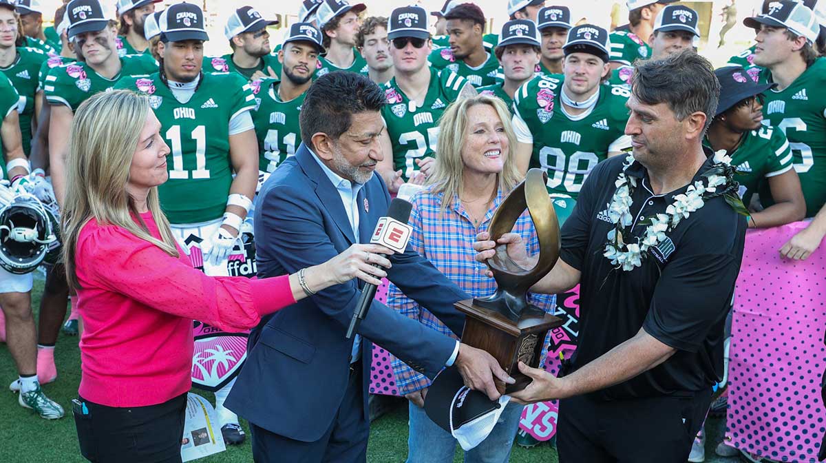 Ohio Bobcats head coach Brian Smith is given the Cure Bowl trophy after beating the Jacksonville State Gamecocks at Camping World Stadium.