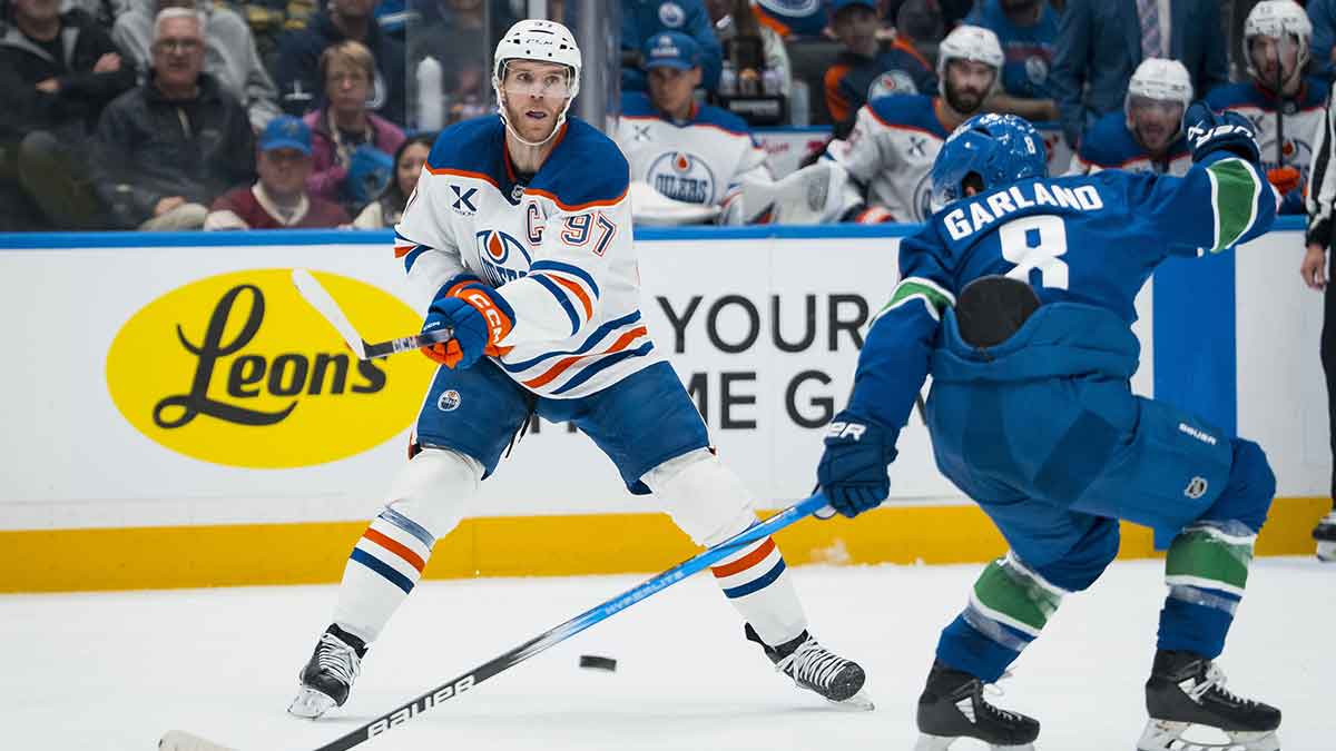 Edmonton Oilers forward Connor McDavid (97) passes around Vancouver Canucks forward Conor Garland (8) in the second period at Rogers Arena.