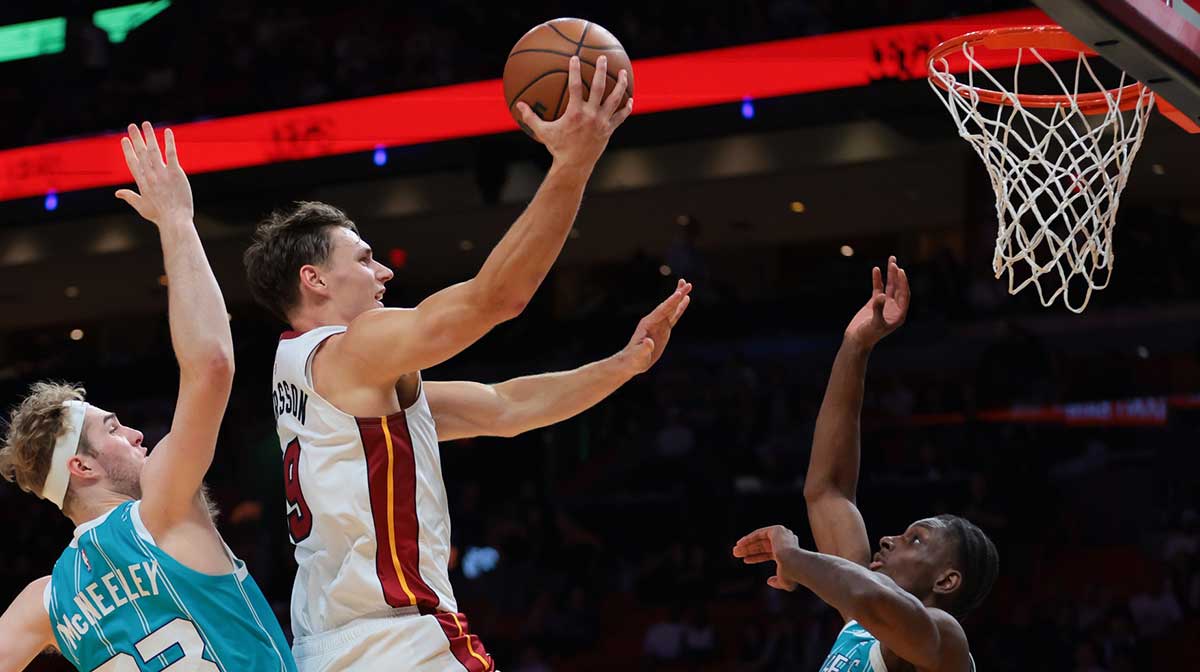 Miami Heat guard Pelle Larsson (9) drives to the basket against Charlotte Hornets forward Liam McNeeley (33) and guard Sion James (4) during the fourth quarter at Kaseya Center.
