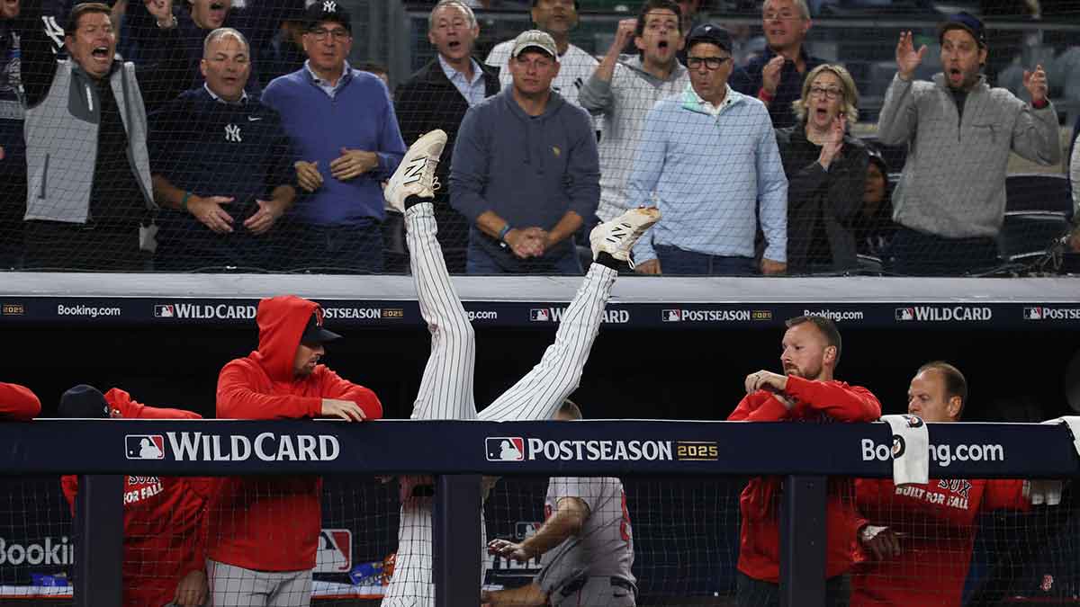 New York Yankees third baseman Ryan McMahon (19) falls into the Boston Red Sox dugout after making a catch of a popup in the eighth inning during game three of the Wildcard round for the 2025 MLB playoffs at Yankee Stadium.