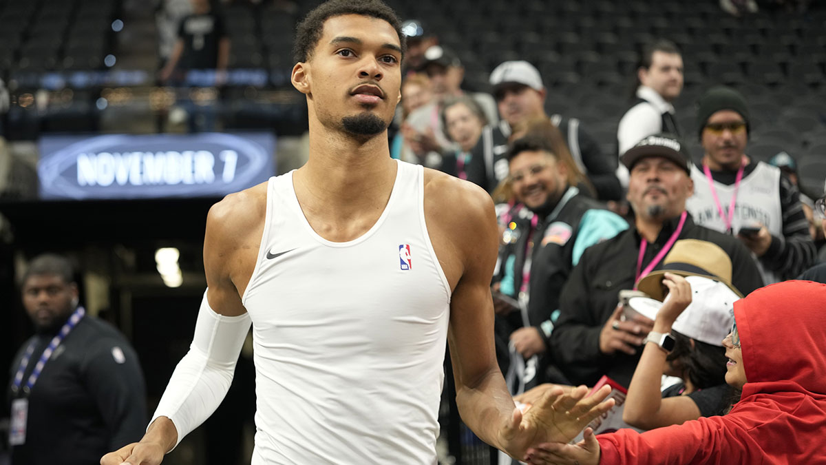 San Antonio Spurs forward Victor Wembanyama (1) greets a young fan while entering the court before a game against the Miami Heat at Frost Bank Center.