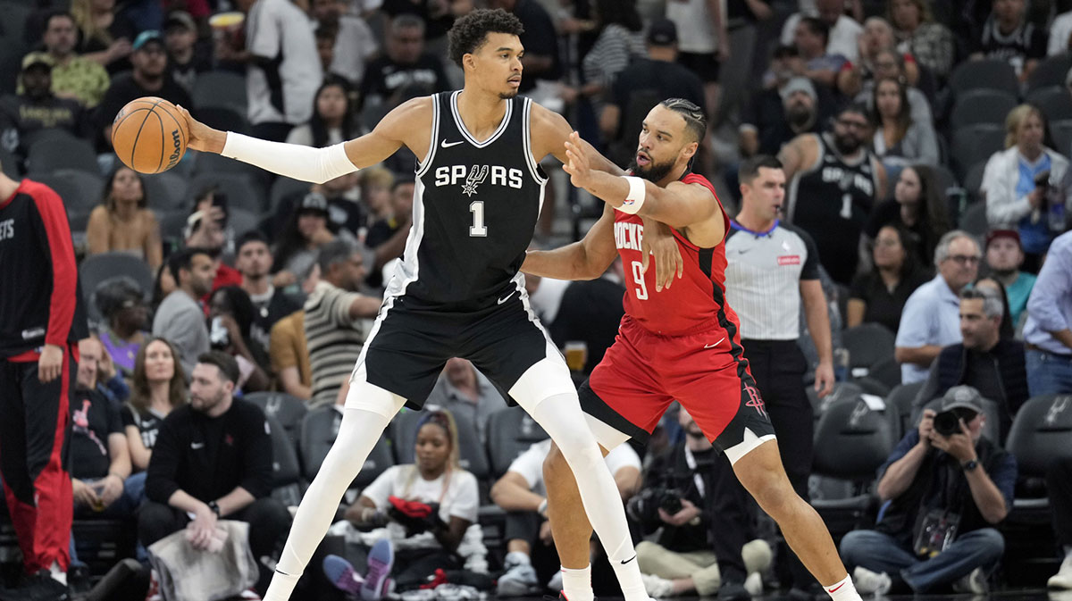 San Antonio Spurs center Victor Wembanyama (1) passes the ball while defended by Houston Rockets guard Dillon Brooks (9) during the first half at Frost Bank Center.