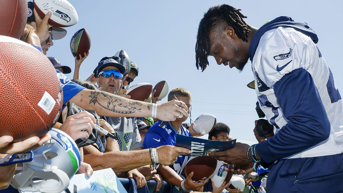 Seattle Seahawks cornerback Tariq Woolen (27) signs autographs following training camp practice at the Virginia Mason Athletic Center. 