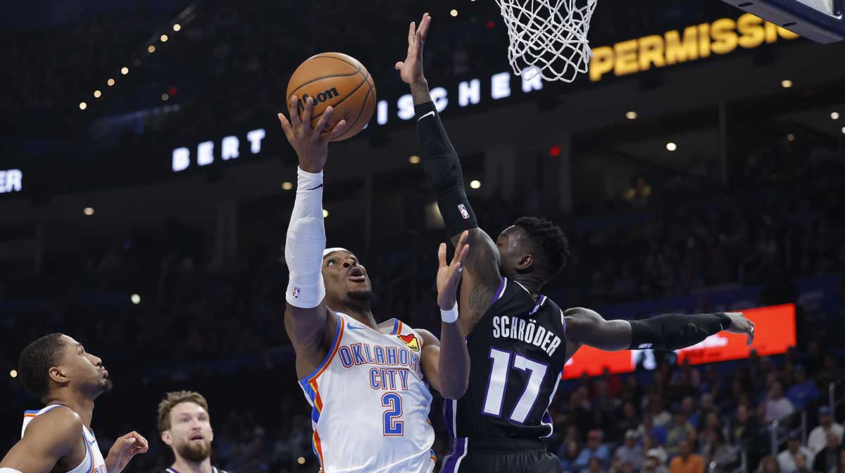 Thunder guard Shai Gilgeous-Alexander (2) shoots as Sacramento Kings guard Dennis Schroder (17) defends during the second half at Paycom Center with Thunder's Jalen Williams and Ajay Mitchell in the background