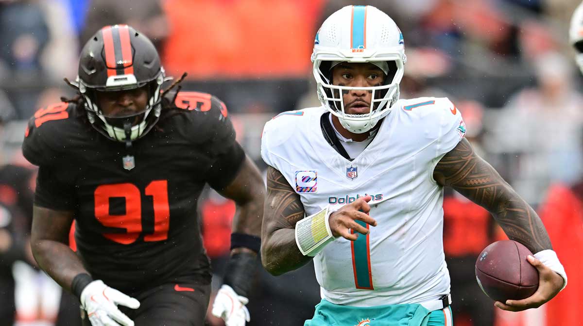 Miami Dolphins quarterback Tua Tagovailoa (1) runs with the ball as Cleveland Browns defensive end Alex Wright (91) defends during the first half at Huntington Bank Field.