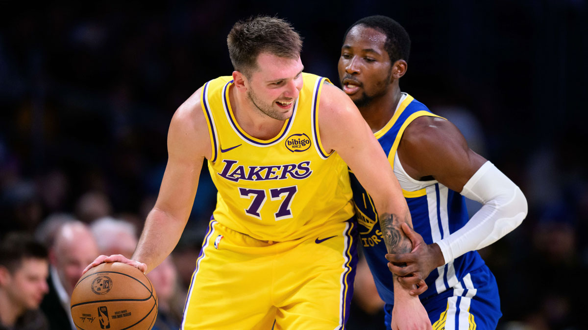 Lakers guard Luka Doncic (77) looks to drive against Golden State Warriors forward Jonathan Kuminga (1) during the second half at Crypto.com Arena with Draymond Green and Warriors head coach Steve Kerr in the background