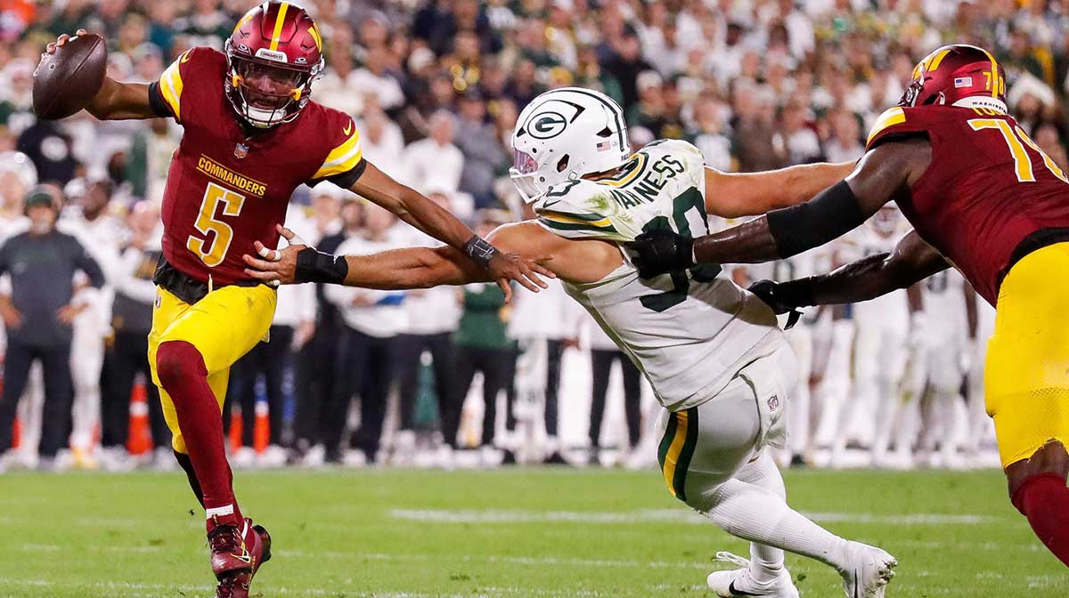 Washington Commanders quarterback Jayden Daniels (5) scrambles away from Green Bay Packers defensive end Lukas Van Ness (90) on Thursday, September 11, 2025, at Lambeau Field in Green Bay, Wis. The Packers won the game, 27-18.