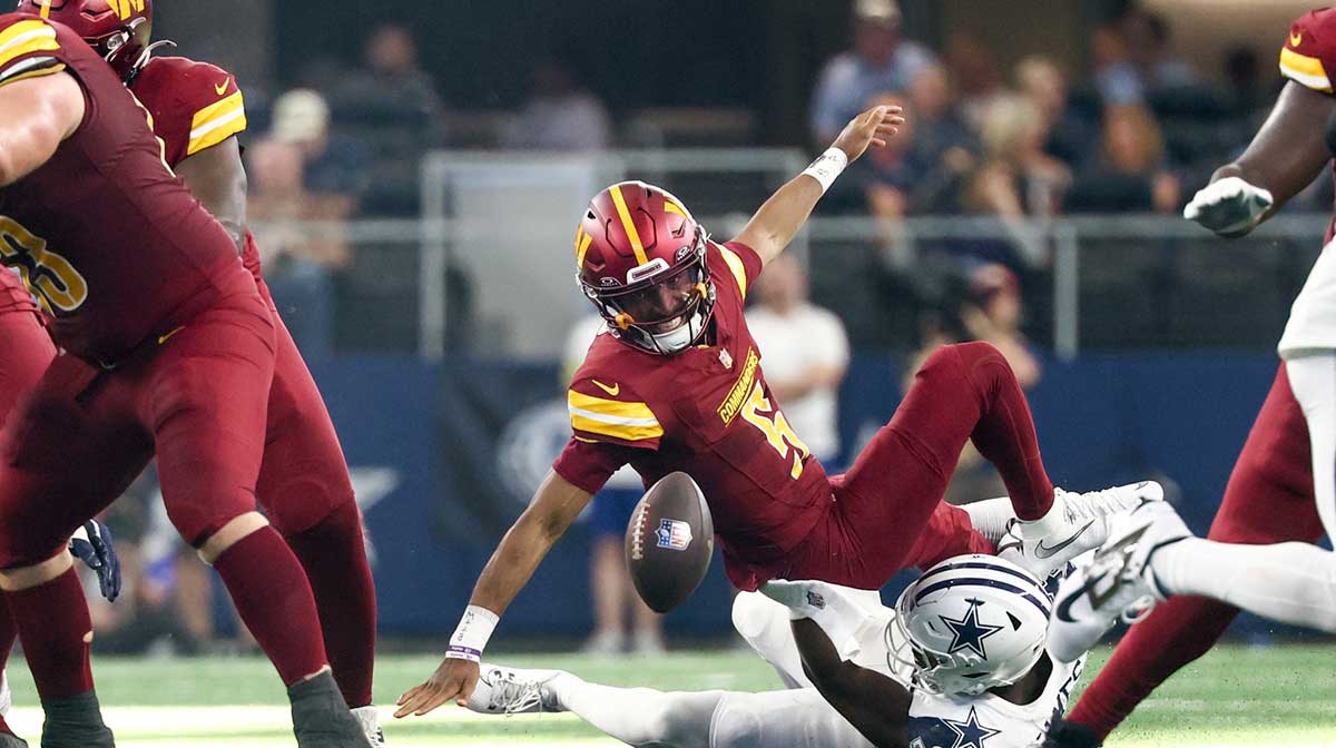 Washington Commanders quarterback Jayden Daniels (5) fumbles the ball defended by Dallas Cowboys linebacker Shemar James (50) during the third quarter of the game at AT&T Stadium.