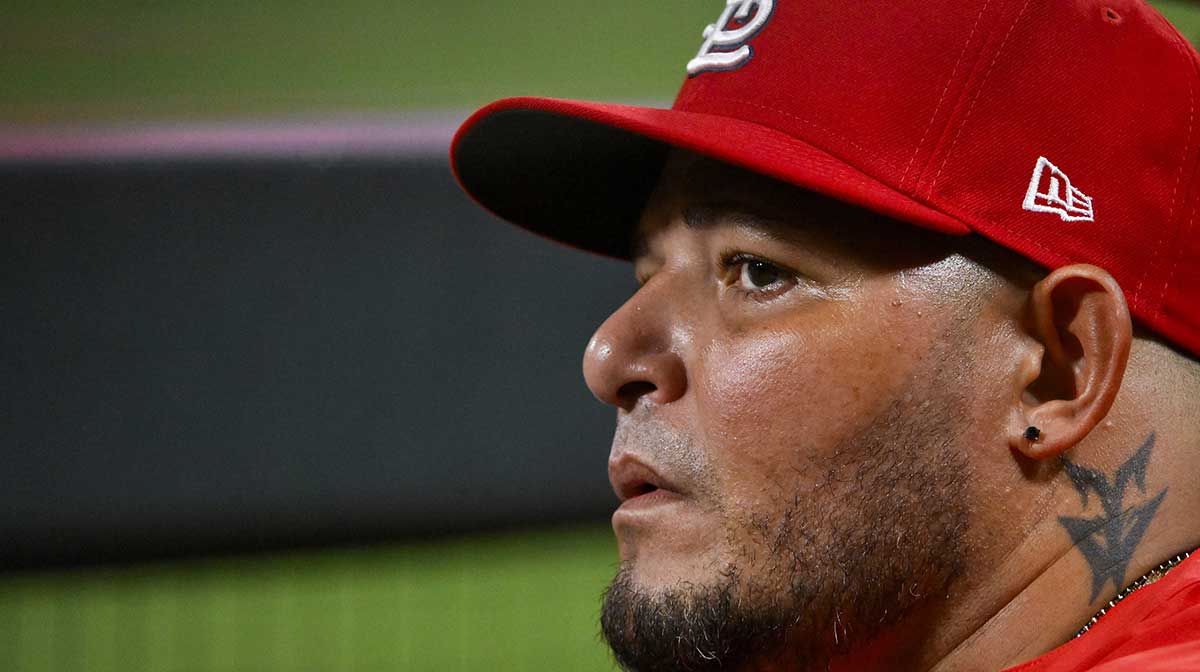 St. Louis Cardinals guest coach Yadier Molina (4) looks on from the dugout during the ninth inning against the Chicago Cubs at Busch Stadium.