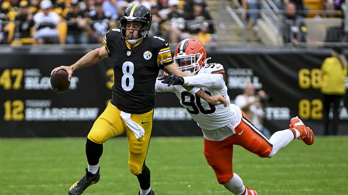Pittsburgh Steelers quarterback Aaron Rodgers (8) attempts to run the ball while Cleveland Browns defensive end Joe Tryon-Shoyinka (90) pursues during the second quarter at Acrisure Stadium.