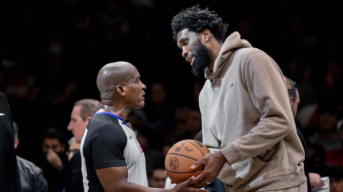 76ers center Joel Embiid (21) chats with referee Derrick Collins (11) during the second half at Barclays Center with the Magic logo in the background