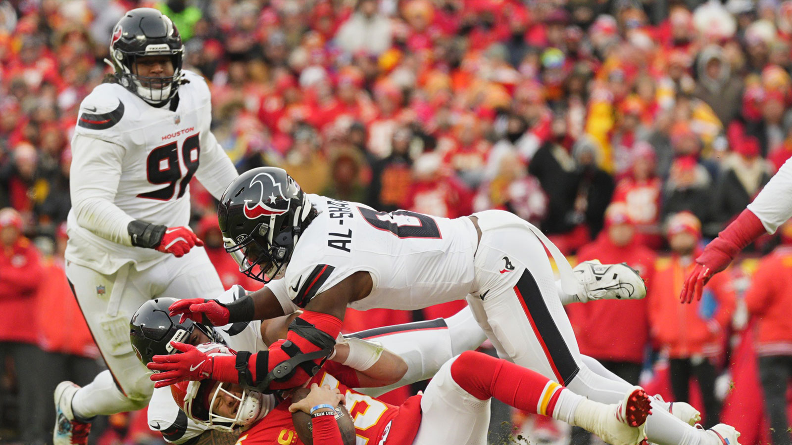 Kansas City Chiefs quarterback Patrick Mahomes (15) is sacked by Houston Texans linebacker Azeez Al-Shaair (top) and defensive tackle Tommy Togiai (72) during the first quarter of a 2025 AFC divisional round game at GEHA Field at Arrowhead Stadium.