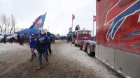 A fan carrying a Bills Mafia flag leaves a parking lot full of tailgaters and heads to the stadium before a 2024 AFC divisional round game between the Buffalo Bills and Kansas City Chiefs at Highmark Stadium.