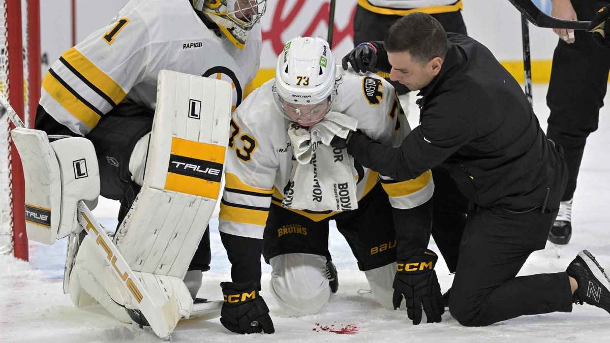 Boston Bruins defenseman Charlie McAvoy (73) is tended by a trainer and teammate goalie Jeremy Swayman (1) after receiving a shot in the mouth during the second period of the game against the Montreal Canadiens at the Bell Centre