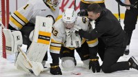Boston Bruins defenseman Charlie McAvoy (73) is tended by a trainer and teammate goalie Jeremy Swayman (1) after receiving a shot in the mouth during the second period of the game against the Montreal Canadiens at the Bell Centre