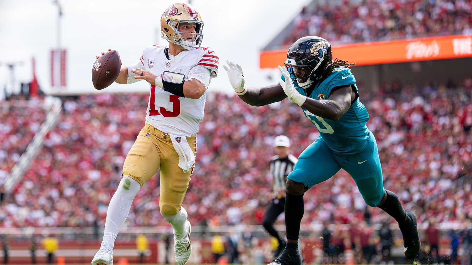 San Francisco 49ers quarterback Brock Purdy (13) runs the football against Jacksonville Jaguars linebacker Devin Lloyd (0) during the second quarter at Levi's Stadium. 