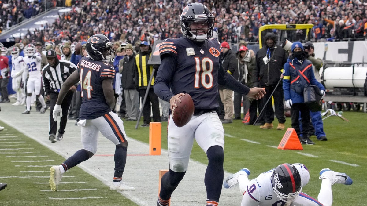 Chicago Bears quarterback Caleb Williams (18) scores the game-winning touchdown against New York Giants linebacker Brian Burns (0) during the fourth quarter at Soldier Field.