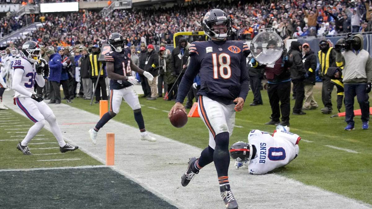 Chicago Bears quarterback Caleb Williams (18) scores the game-winning touchdown against New York Giants linebacker Brian Burns (0) during the fourth quarter at Soldier Field.