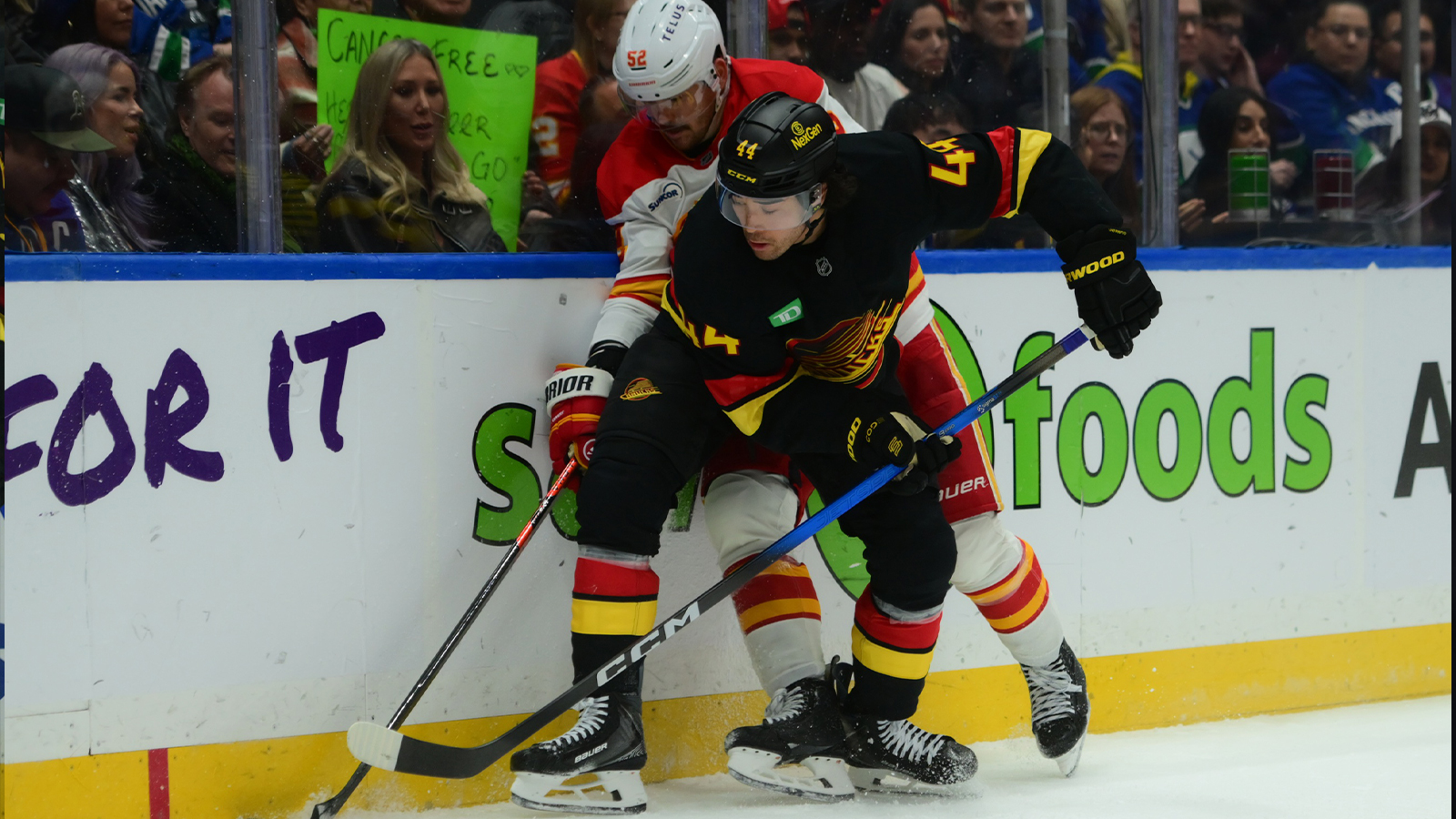 Vancouver Canucks left wing Kiefer Sherwood (44) battles for the puck against Calgary Flames defenseman Mackenzie Weegar (52) during the third period at Rogers Arena.
