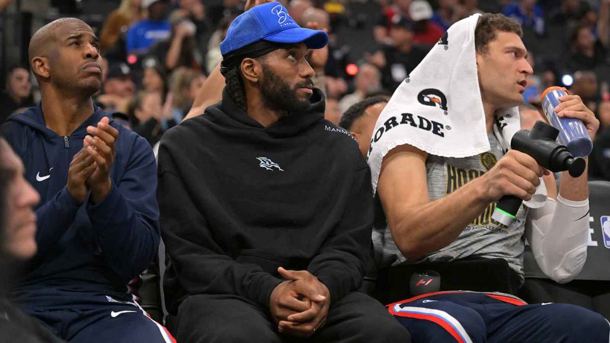 Clippers guard Chris Paul (3), forward Kawhi Leonard (2) and center Brook Lopez (11) on the bench during the first half against the Phoenix Suns at Intuit Dome with Vince Staples in the background