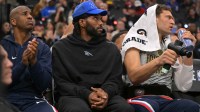 Clippers guard Chris Paul (3), forward Kawhi Leonard (2) and center Brook Lopez (11) on the bench during the first half against the Phoenix Suns at Intuit Dome with Vince Staples in the background