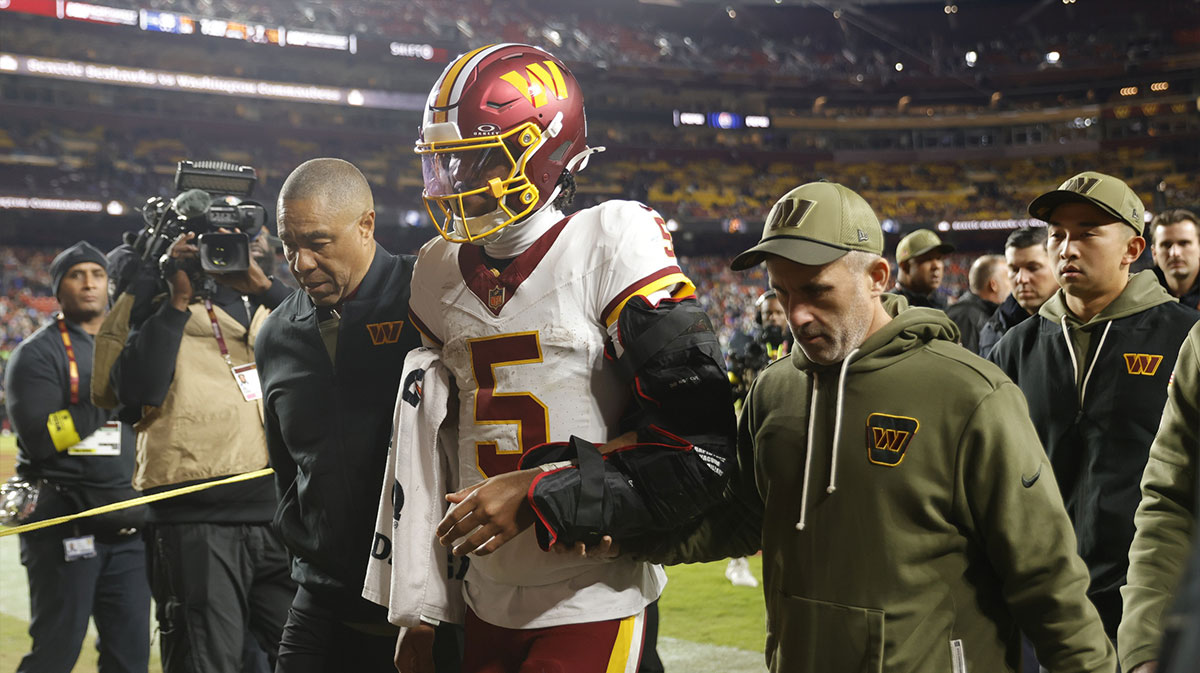 Washington Commanders quarterback Jayden Daniels (5) is helped off the field after an injury during the second half against the Seattle Seahawks at Northwest Stadium.