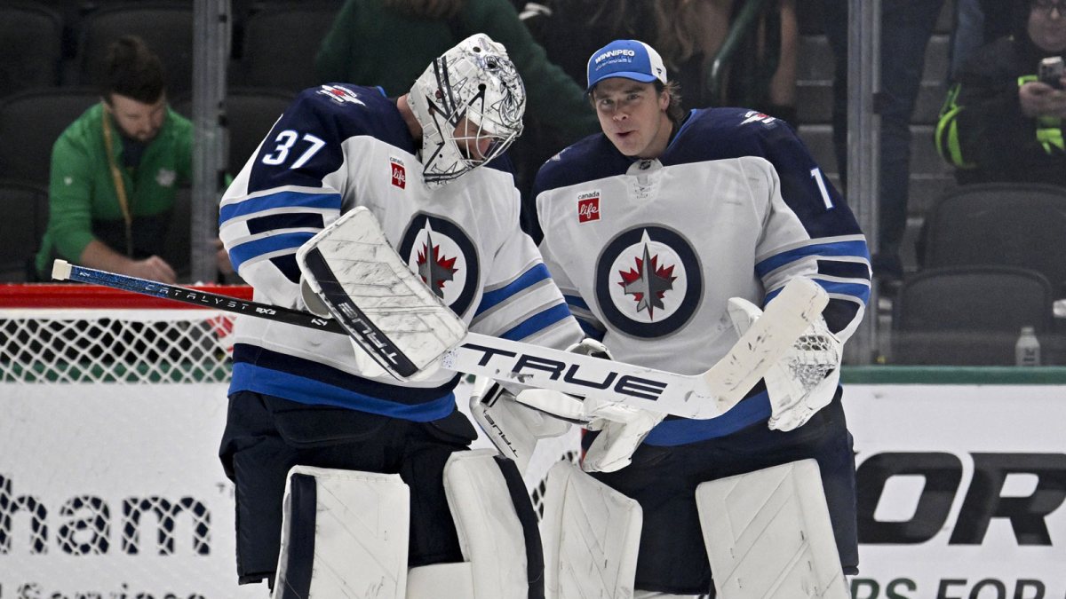 Winnipeg Jets goaltender Connor Hellebuyck (37) and goaltender Eric Comrie (1) celebrate on the ice after Hellebuyck gets the shutout win over the Dallas Stars at the American Airlines Center.