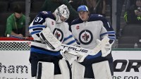 Winnipeg Jets goaltender Connor Hellebuyck (37) and goaltender Eric Comrie (1) celebrate on the ice after Hellebuyck gets the shutout win over the Dallas Stars at the American Airlines Center.