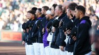 Members of the Colorado Rockies line up during the national anthem before the game against the Athletics at Coors Field.