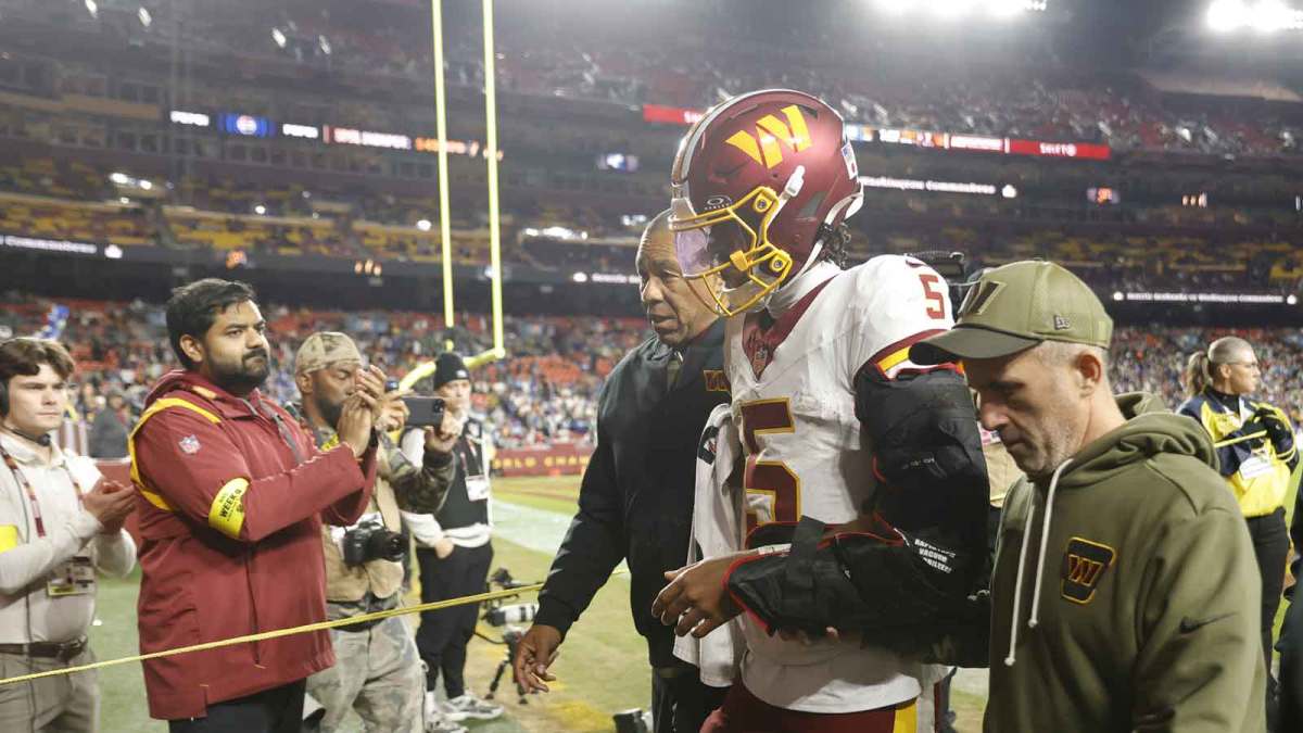 Washington Commanders quarterback Jayden Daniels (5) is helped off the field after an injury during the second half against the Seattle Seahawks at Northwest Stadium.