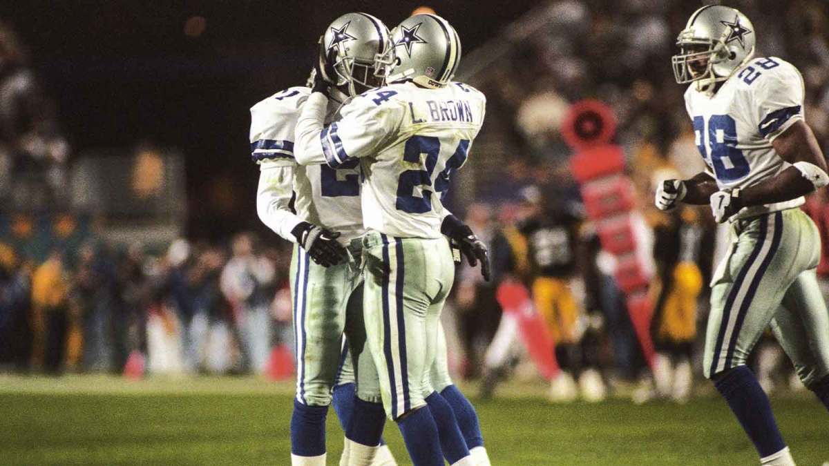 Dallas Cowboys cornerback Larry Brown (24) reacts on the field with teammates Deion Sanders (21) and Darren Woodson (28) during Super Bowl XXX against the Pittsburgh Steelers at Sun Devil Stadium. The Cowboys defeated the Steelers 27-17.