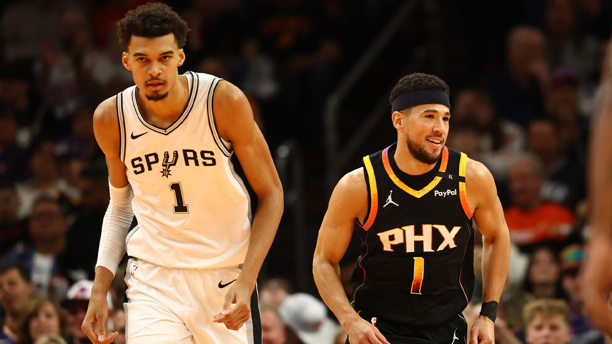 Phoenix Suns guard Devin Booker (right) against San Antonio Spurs center Victor Wembanyama in the first half of an NBA Cup game at Footprint Center.
